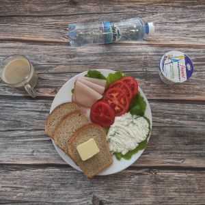 Zdjęcia przedstawiają Dietę z ograniczeniem łatwostrawnych węglowodan&oacute;w: Masło extra Szynka Piastowska Sałata zielona Kawa zbożowa z mlekiem Chleb Graham Jogurt naturalny Twarożek z koperkiem Woda mineralna Pomidor